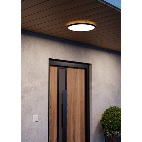 Minerario LED Flush Ceiling Light, 39cm round black fixture with white diffuser, illuminated warm white over a wooden porch ceiling above a wood and black front door.