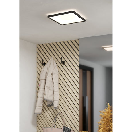 Minerario LED Panel Light 29 x 29cm in black, square ceiling fixture with white diffuser, shown mounted above a hallway with coat hooks and wall panelling.