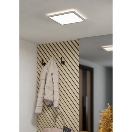 Square white LED ceiling panel light, Minerario 29 x 29cm, installed flush on a hallway ceiling above a wood-slat wall with coat hooks.