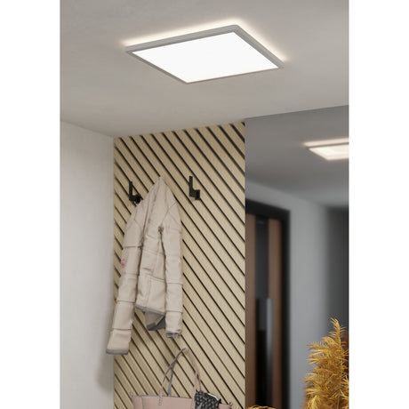 Minerario square LED ceiling panel light in white plastic, 39 x 39cm, shown recessed into a hallway ceiling beside a mirror and slatted wood wall with coat hooks.