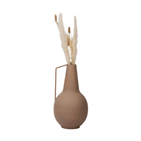 Miouski Metal Vase in matt sand finish, a rounded jug-shaped vase with tall tapering neck and angled side handle, shown with dried pampas grass stems on a plain white background.
