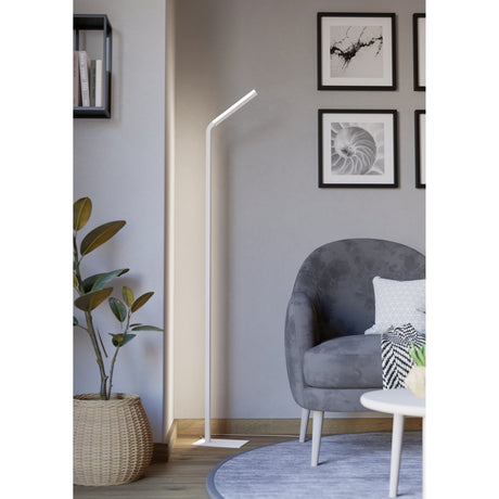 Mirante LED Floor Lamp in white steel and aluminium, with a slim pole bending into an angled head on a flat base, shown beside a grey armchair in a living room.