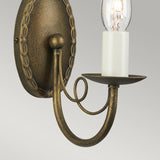 Introducing the Minster 1 Light Wall Light in Black/Gold Patina: a vintage-inspired wall sconce providing ambient lighting with an elegant finish and exposed bulb design. It boasts an ornate curved arm and an oval backplate adorned with a decorative braided edge, ideal for adding charm to any space. The bulb is mounted on a candle-like holder, enhancing its timeless appeal.