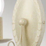 Close-up of the Minster 1 Light Wall Light in Ivory/Gold Patina, featuring a vintage-style design with a textured, oval backplate and ivory decorative detailing. The arm with hints of gold patina elegantly curves outward to support an unlit light bulb, visible against the neutral background.