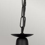 Close-up of the Minster 3 Light Chandelier in a sleek black finish, featuring a semi-flush fitting design with a curved base and a thick chain elegantly wrapped in wire. The background is a plain, light gray color.