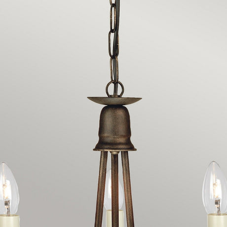 A close-up of the Minster 3 Light Chandelier showcases its vintage charm with a dark metal chain and semi-flush fitting design. This fixture is adorned with candle-shaped light bulbs and displays a rustic, gold patina on its weathered metal components, set against a neutral backdrop.