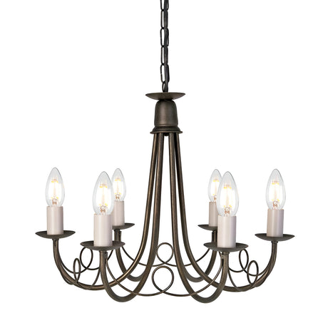 The Minster 6 Light Chandelier in Black/Gold Patina boasts a vintage aesthetic, featuring six upward-curved arms each holding a candle-shaped bulb. Elegantly suspended by a chain, this piece is adorned with intricate scrollwork and exudes timeless charm.