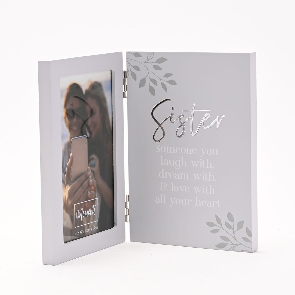 Hinged grey photo frame opening like a book, with a 6 x 4in portrait photo on the left panel and "Sister" in silver script above a white verse on the right, set against a plain white background.