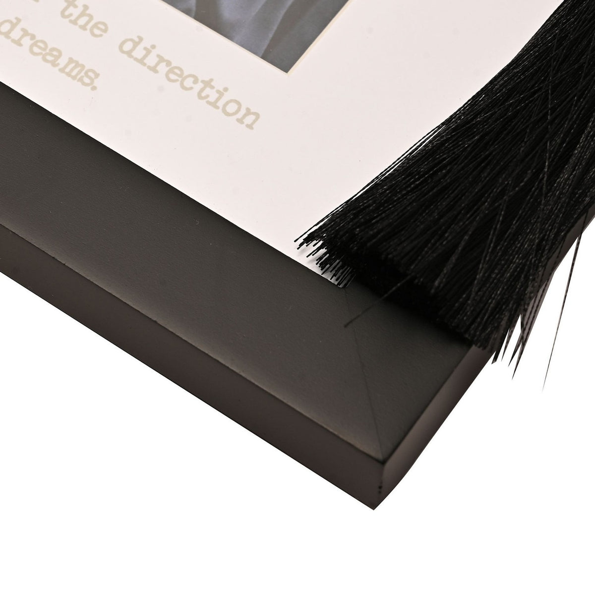 Close-up of the Graduation wooden photo frame's black matt corner with a black tassel hanging from a silver-coloured stud, set against a white mount with printed text.