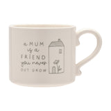 White stoneware mug with curved handle, printed with "a MUM is a FRIEND you never OUT GROW" beside a line-drawn house and flower, shown on a plain white background.