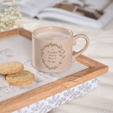 Brown stoneware mug with curled handle and floral wreath design reading "A lucky few have a MUM like you", filled with coffee on a wooden tray beside biscuits.