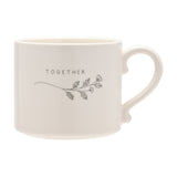 White glazed stoneware mug with curled handle, printed "TOGETHER" text and a grey floral sprig design, shown on a plain white background.