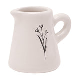 Off-white glazed ceramic mini jug ornament with curved handle and a fine black sketched flower stem design, shown on a plain white background.