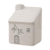 White ceramic mini house ornament with ribbed roof, chimney, and line-drawn door, window, and leaf branch design, shown on a plain white background.