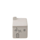 White ceramic mini house ornament with ribbed roof, chimney, four-pane window, arched door, and leaf branch line drawing, on a plain white background.