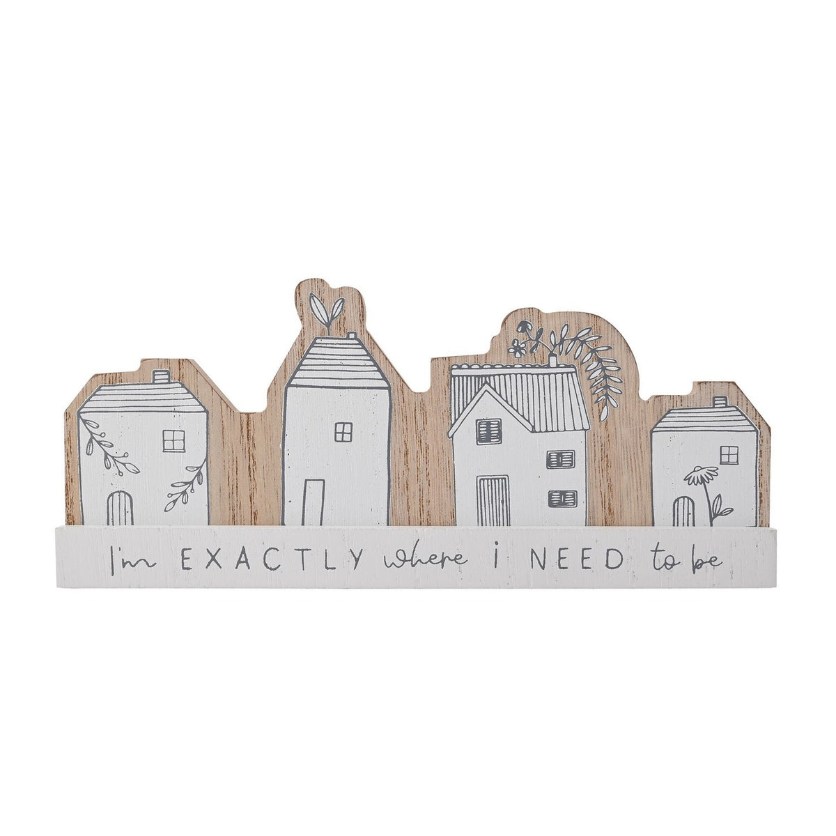 Wooden mantel plaque with four white house silhouettes in grey linework and floral details, on a base reading "I'm EXACTLY where i NEED to be", set against a plain white background.