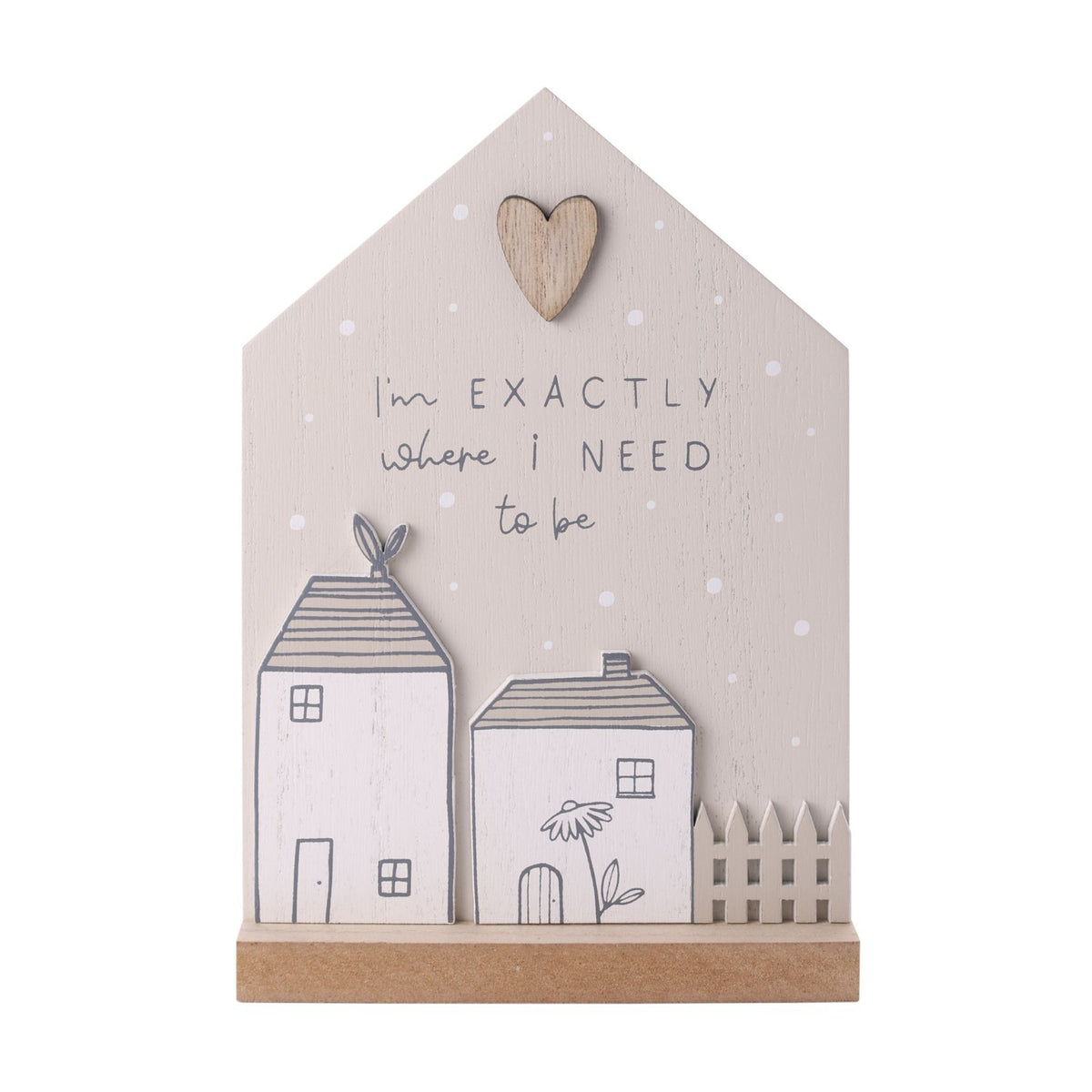 Grey wooden house-shaped plaque with "I'm exactly where I need to be" text, a small wooden heart, two raised white cottage cutouts, and a picket fence detail on a wood base.