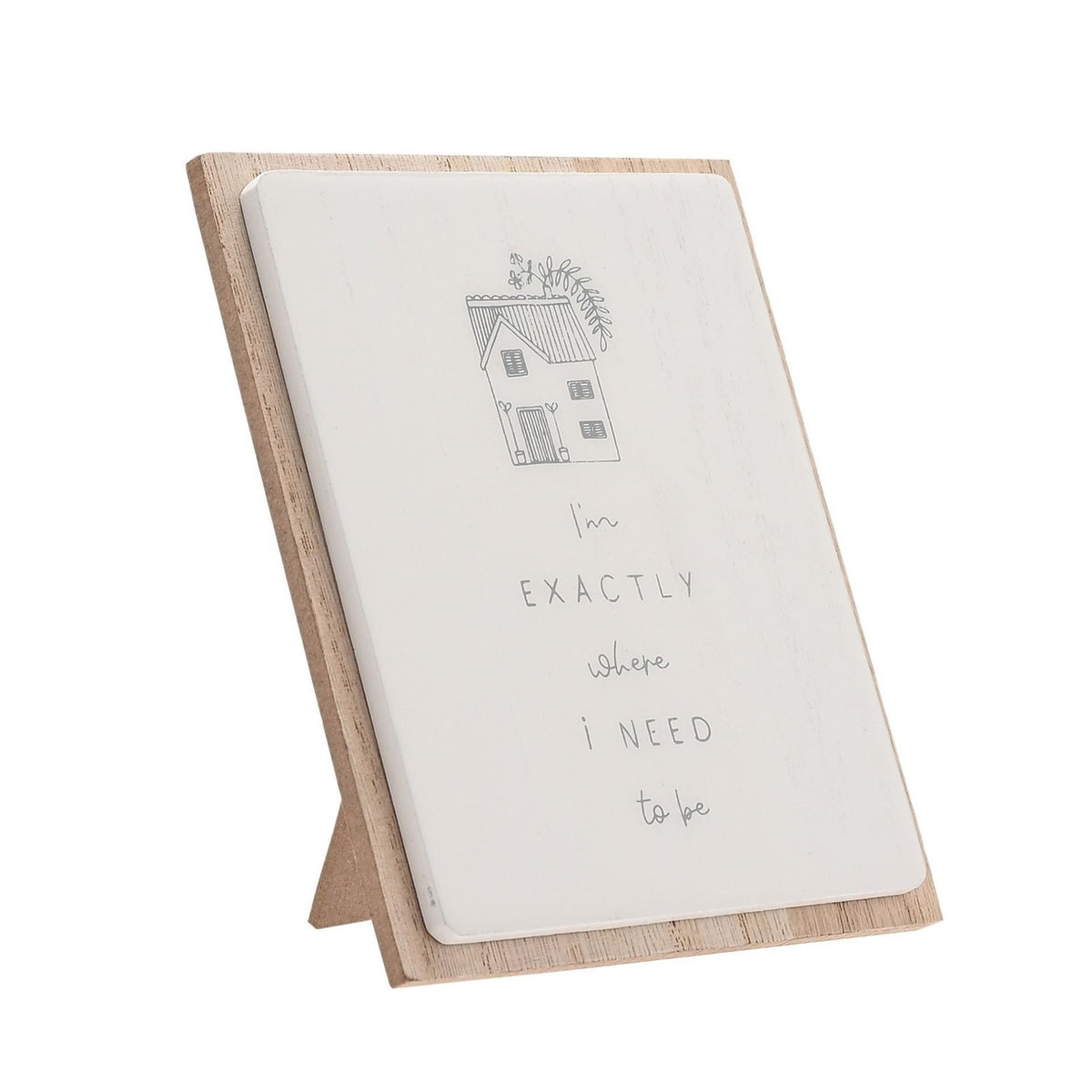 White layered wooden plaque on stand with house line drawing and "I'm exactly where i need to be" text, set on a plain white background.