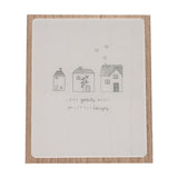 Wooden plaque with easel stand, featuring a white panel on natural wood backing, hand-drawn grey houses, hearts, and "Love grows best in little houses" lettering.