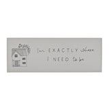 White wooden rectangular mantel plaque with a line-drawn house illustration and the handwritten text "I'm EXACTLY where i NEED to be" on a plain background.
