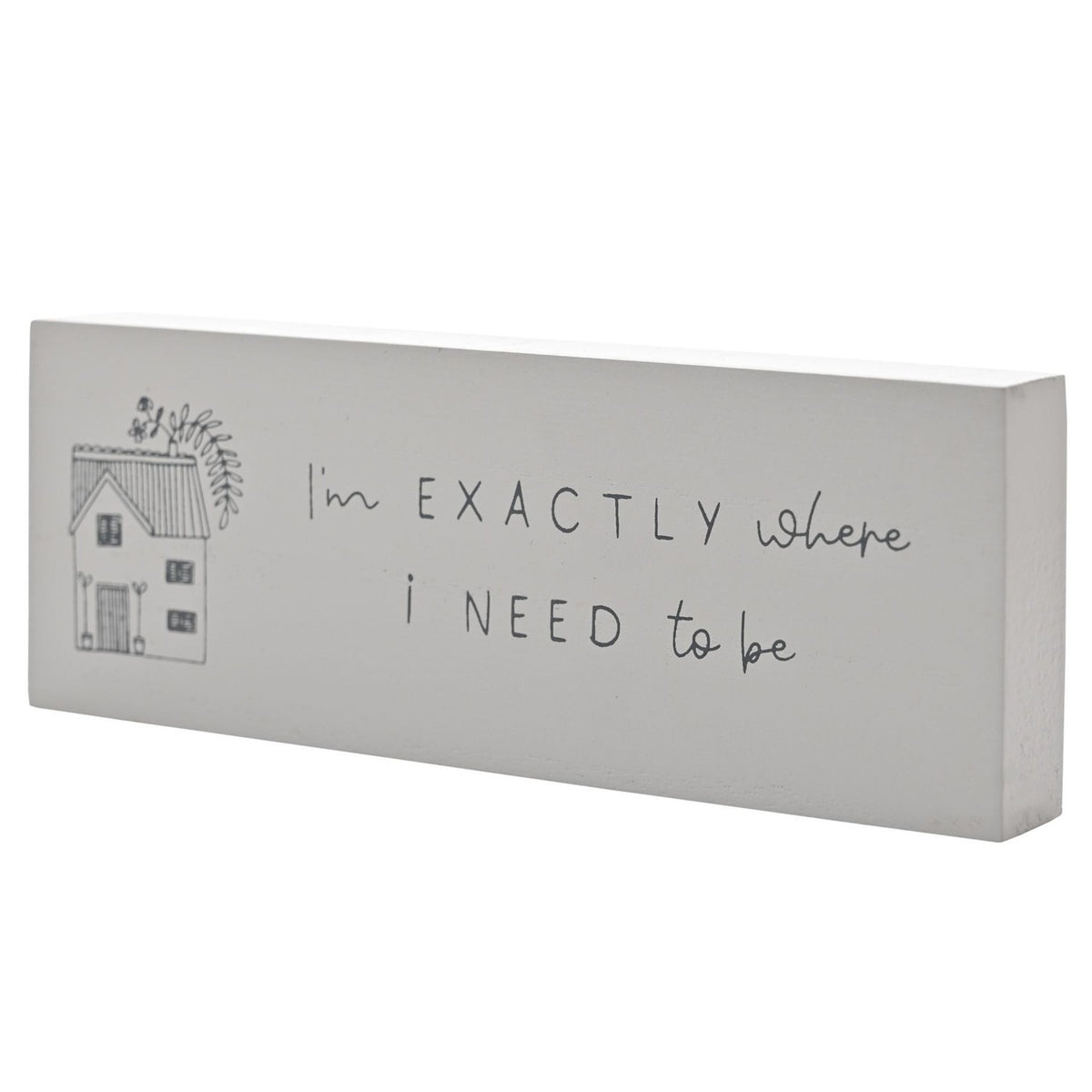 White wooden mantel plaque with a grey house line drawing and "I'm EXACTLY where i NEED to be" text, shown at an angle on a plain background.