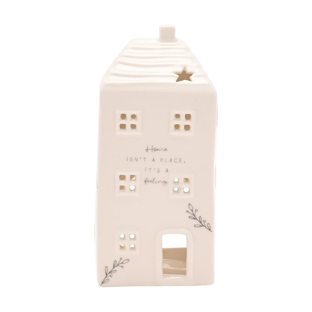 White ceramic cut-out house tea light candle holder with ridged roof, chimney, star cut-out, pierced windows, and "Home isn't a place, it's a feeling" text, on a plain background.
