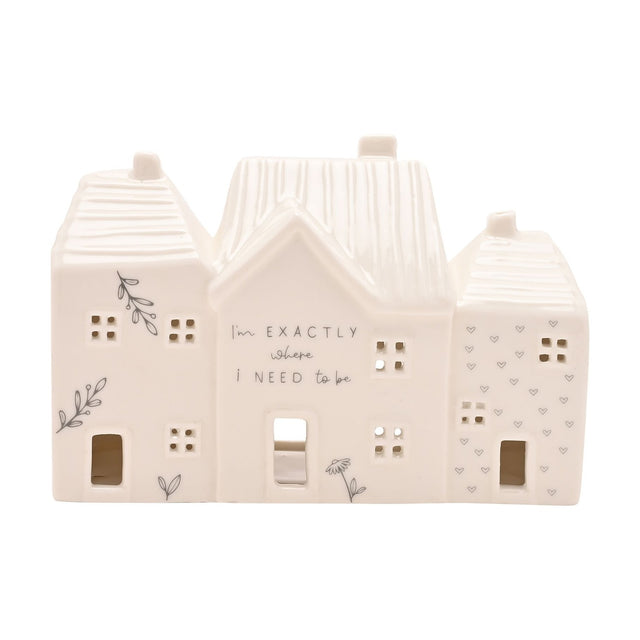 White ceramic tea light holder shaped like three terraced houses with ribbed roofs, chimneys, cut-out windows, botanical and heart details, centre reads Im exactly where I need to be.