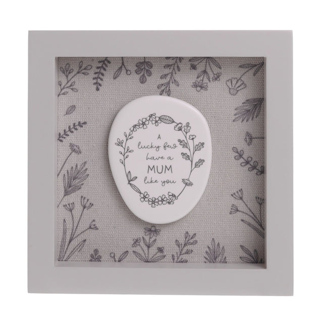 Square grey wood-framed plaque, 15cm x 15cm, with a white pebble-shaped oval reading "A lucky few have a MUM like you" within a floral wreath, set against a wildflower-print background.
