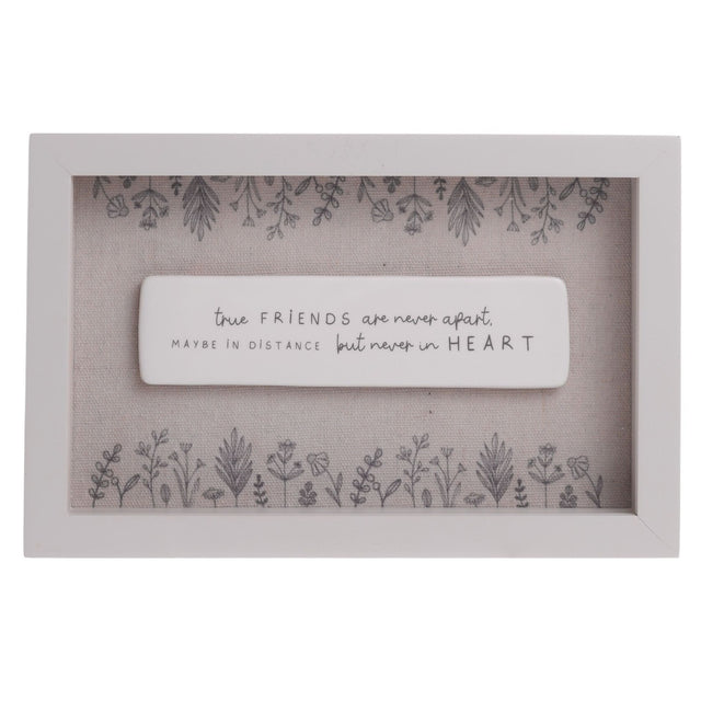 Off white wooden framed wall plaque with a raised white centre panel reading "true FRIENDS are never apart, maybe in distance but never in HEART", bordered by grey floral sprigs on a beige background.