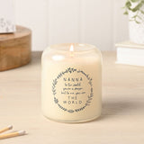 Lit round glass scented candle with cream wax, printed with a grey leafy wreath and "Nanna to the world... THE WORLD" sentiment, displayed on a wooden surface.