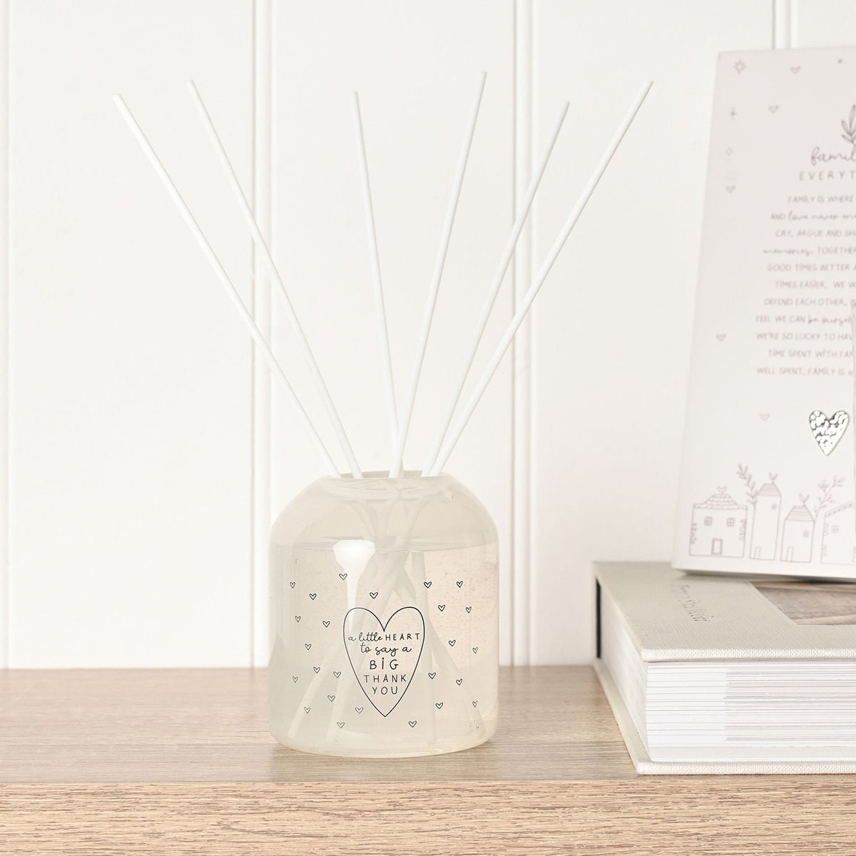 Thank You Heart Print Reed Diffuser 200ml in cream glass with grey heart dots and white reeds, displayed on a wooden shelf beside books.