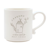 Cream ceramic mug with curved handle, featuring a line-drawn house between leafy sprigs, "GRANDMA" arched above and "another word for best friend" below, on a plain white background.