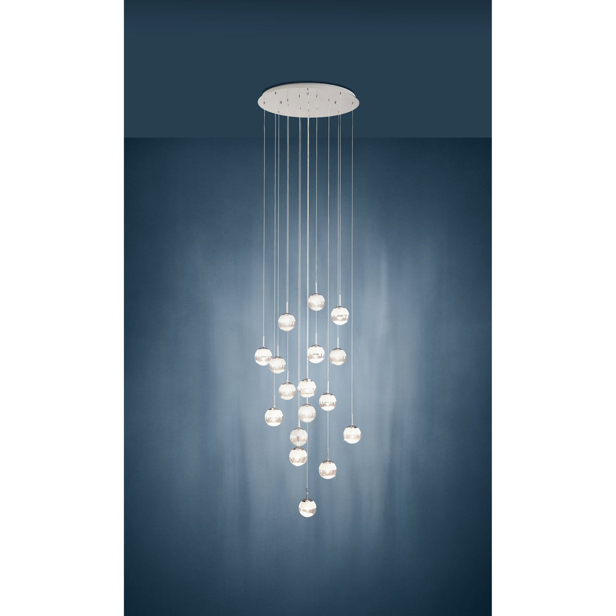 Montefio 2 Glass 17 Light Pendant in chrome, round ceiling plate with clear glass globes cascading at varied lengths, shown against a dark blue wall.