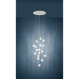 Montefio 2 Glass 17 Light Pendant in chrome, round ceiling plate with clear glass globes cascading at varied lengths, shown against a dark blue wall.