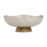 Monywa decorative bowl in cream-coloured metal with a wavy, organic rim, raised on a short wooden pedestal foot, shown on a plain white background.