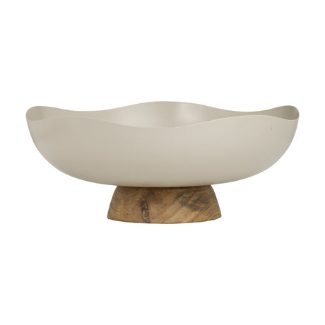 Monywa decorative bowl in cream-coloured metal with a wavy, organic rim, raised on a short wooden pedestal foot, shown on a plain white background.