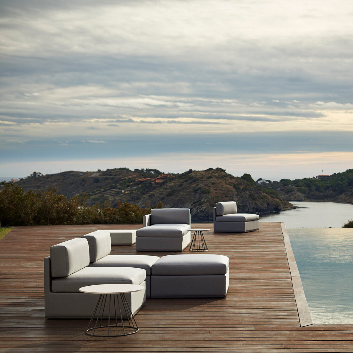 Mood XL Upholstered Garden Footstool in light grey outdoor fabric, 89 x 89cm square design, shown on a wooden poolside deck with matching modular sofa seating.