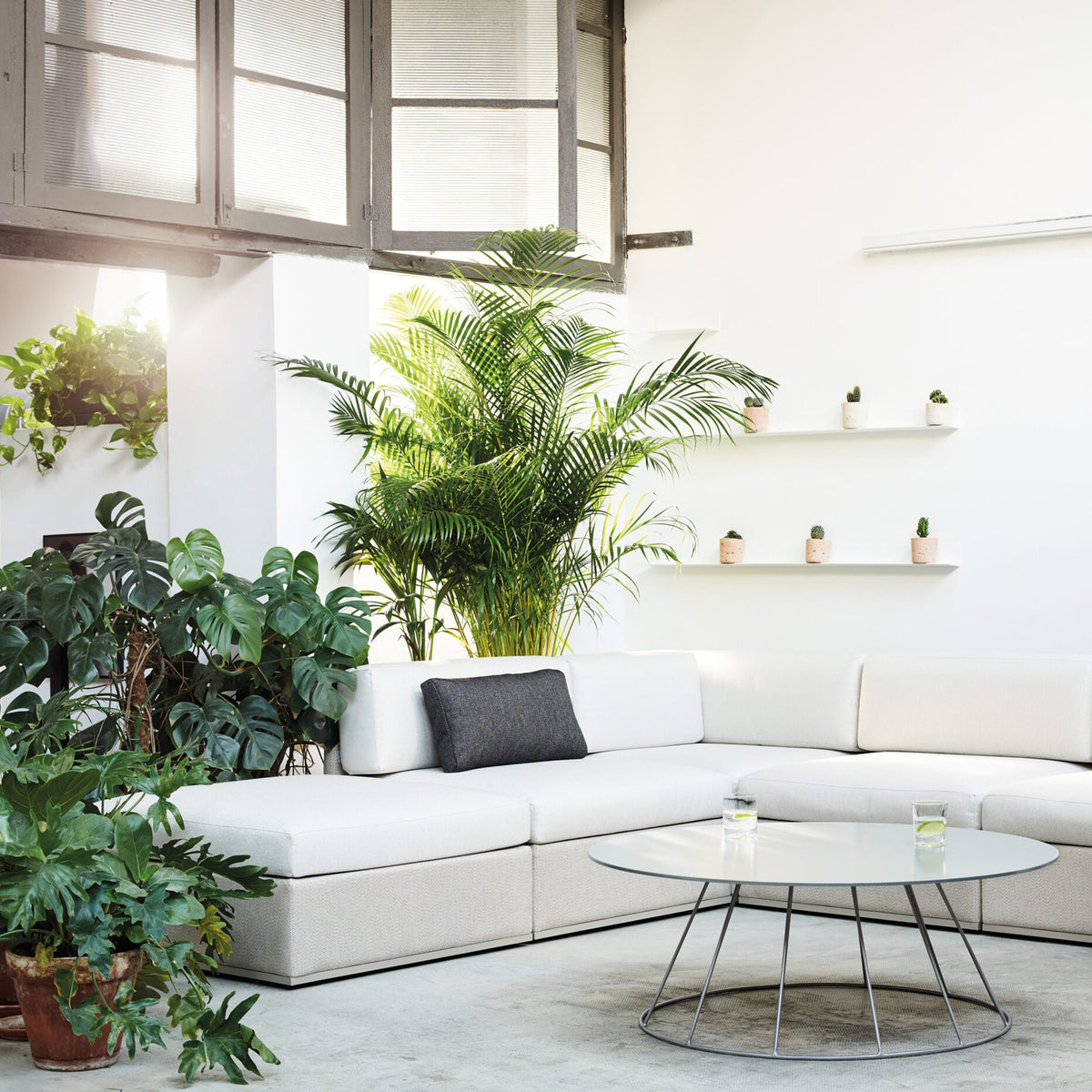 Mood XL Upholstered Garden Footstool in white, square-shaped with a removable cushioned top, clean straight sides, and aluminium legs, shown in a bright living room setting.