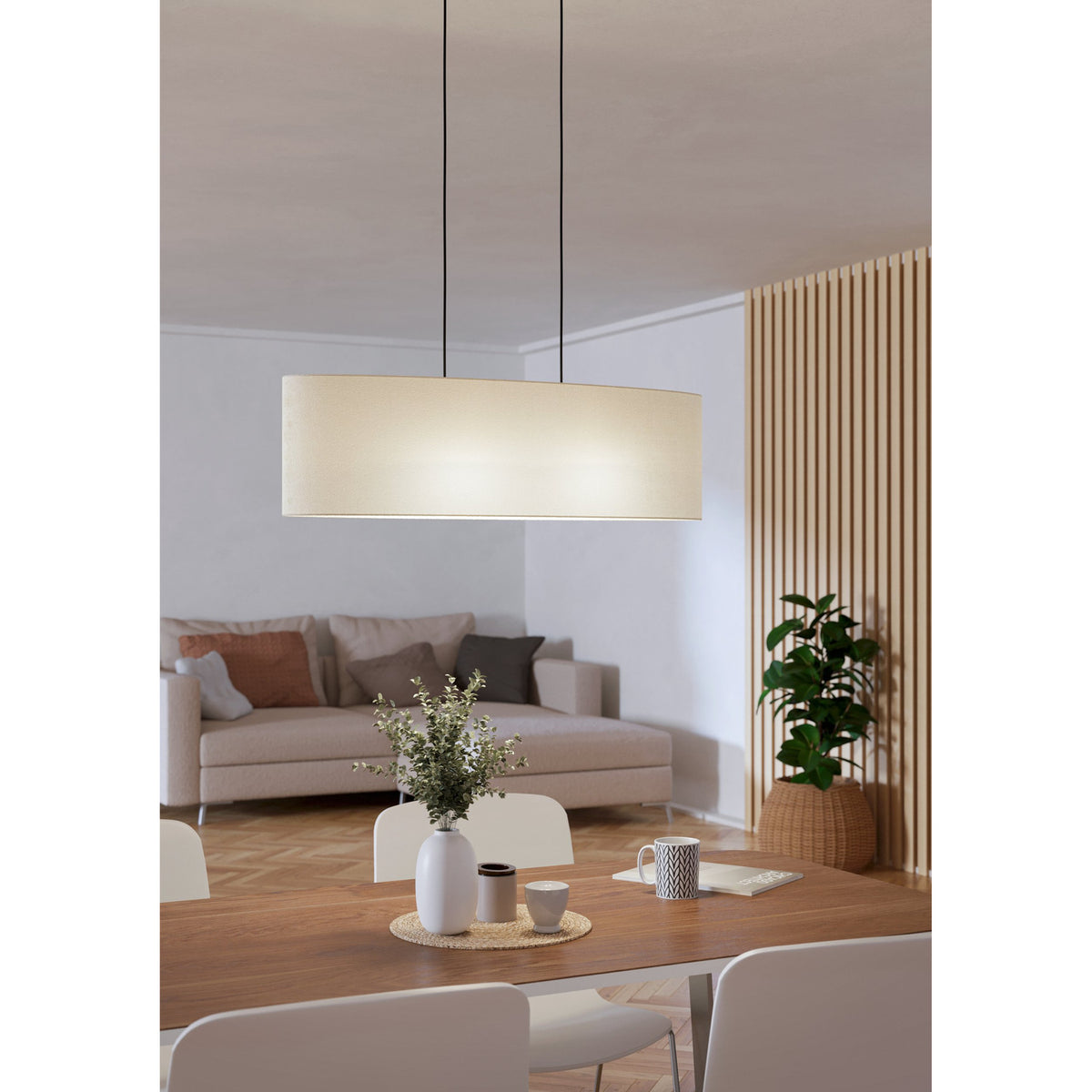 Morbarne Fabric 2 Light Pendant in Black, oval cream fabric drum shade on black cords, hung above a dining table in a living and dining space.