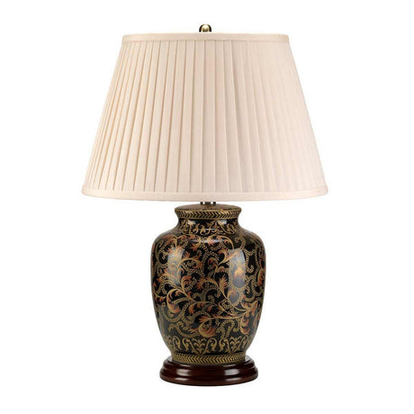 The Morris 1 Light Small Table Lamp - Gold & Black features an ornate ceramic base adorned with golden floral designs on a dark background, complemented by an elegant pleated cream-colored fabric lampshade resting gracefully on a round wooden base.