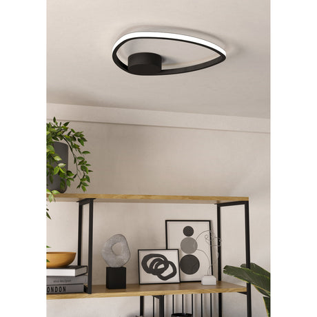 Moschella LED flush ceiling light in black, an open rounded-triangle ring with white LED diffuser edge, mounted flush to a light grey ceiling above a wooden shelving unit with decor.