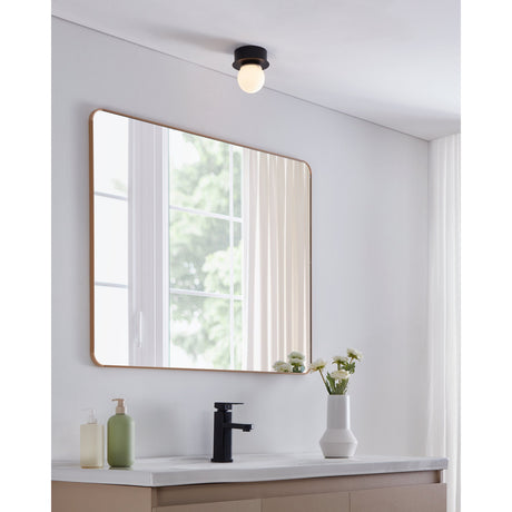 Mosiano LED Bathroom Ceiling Light in black steel with opal glass globe, mounted flush on a white ceiling above a mirror in a bathroom setting.