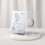 Clear glass photo frame for a 6 x 4in picture, with bevelled edges and a round silver 18th Birthday badge, standing on a white marble base.