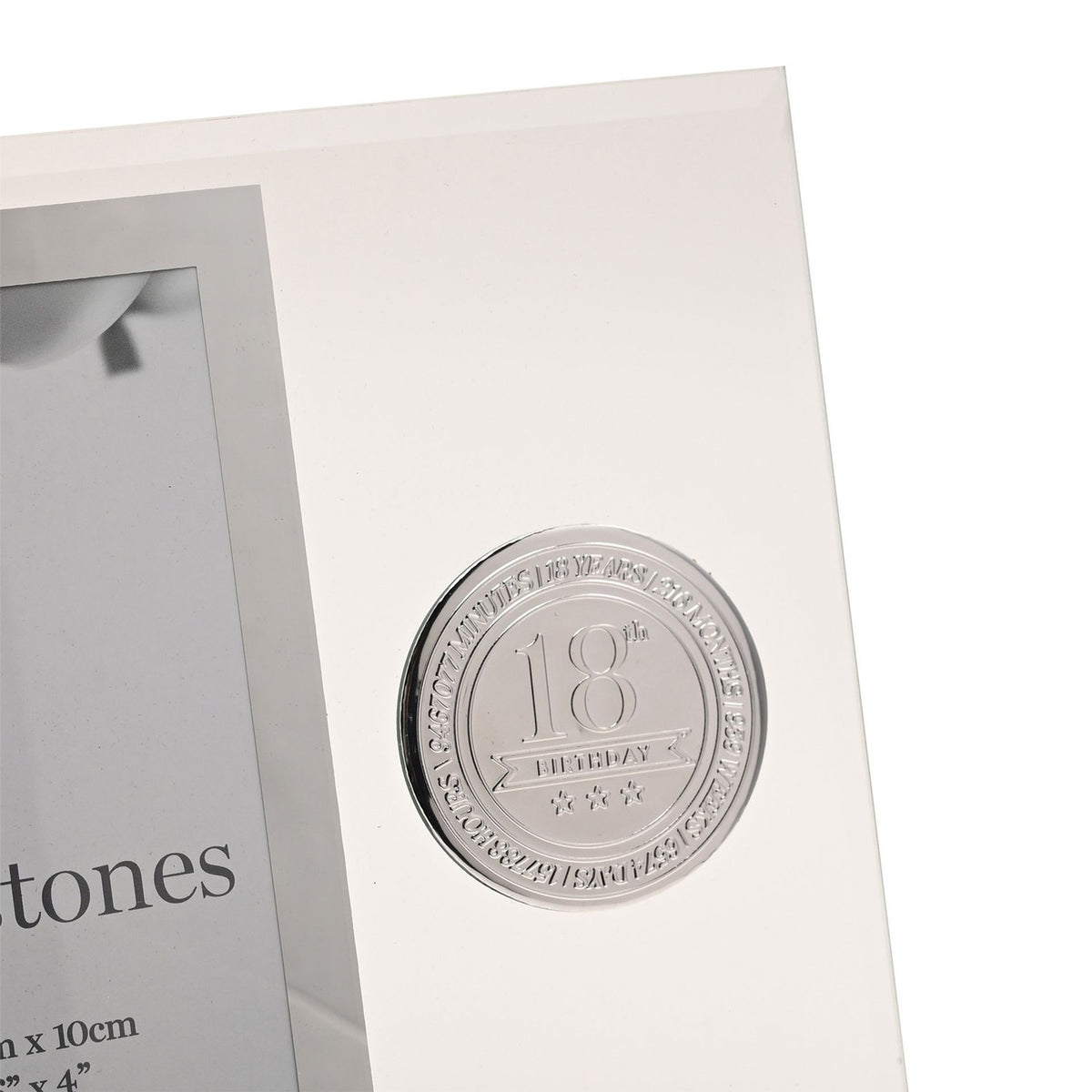Close-up of clear glass photo frame with bevelled edge, showing round silver metal 18th Birthday badge with star details beside the rectangular picture window.