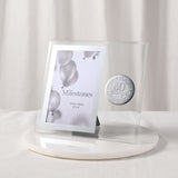 Glass photo frame with silver 50th birthday metal badge beside a 6 x 4in portrait opening, clear glass and silver-grey border, displayed on a marble base against a light background.