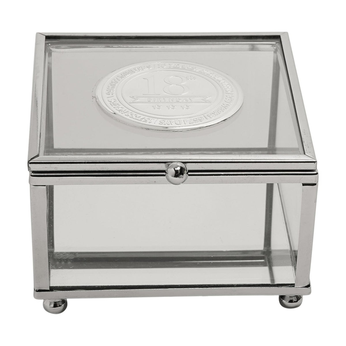 Square glass trinket box with slim silver metal frame and ball feet, featuring a round silver metal badge on the lid engraved "18th Birthday," on a plain white background.