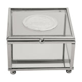 Square glass trinket box with slim silver metal frame and ball feet, featuring a round silver metal badge on the lid engraved "18th Birthday," on a plain white background.