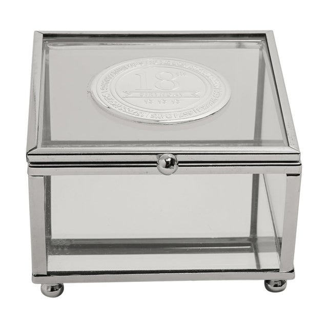 Square glass trinket box with slim silver metal frame and ball feet, featuring a round silver metal badge on the lid engraved "18th Birthday," on a plain white background.