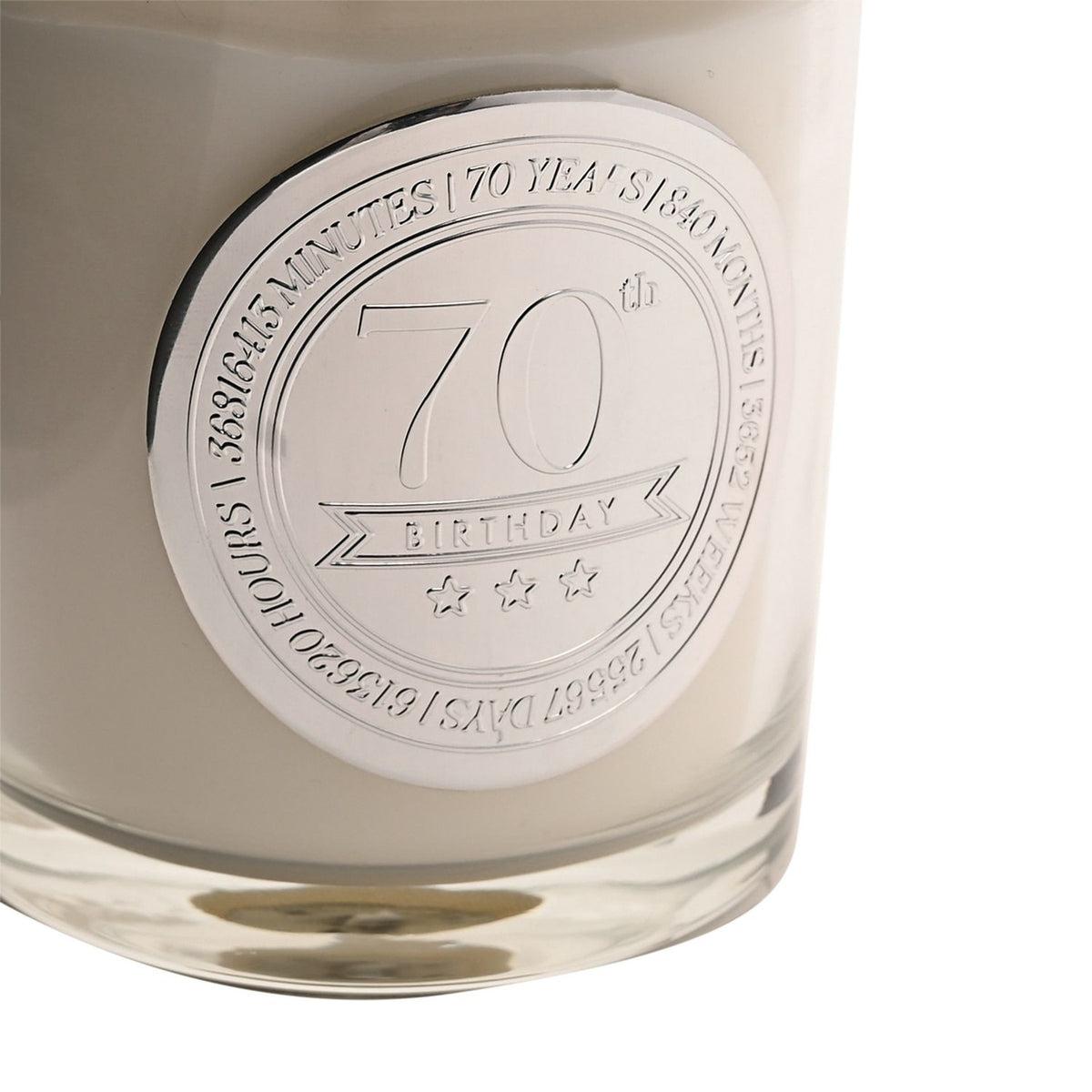 Close-up of a 70th Birthday sandalwood scented candle in a clear glass vessel with a round silver medallion reading "70th Birthday" and time units engraved around its rim.