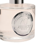Close-up of the 70th Birthday Sandalwood Reed Diffuser 200ml, clear glass bottle with silver cap and round silver medallion marking 70 years, on a white background.